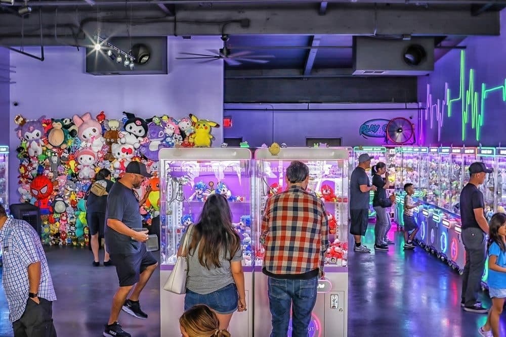 Guests of all ages spread across the arcade floor, playing the claw machines together.