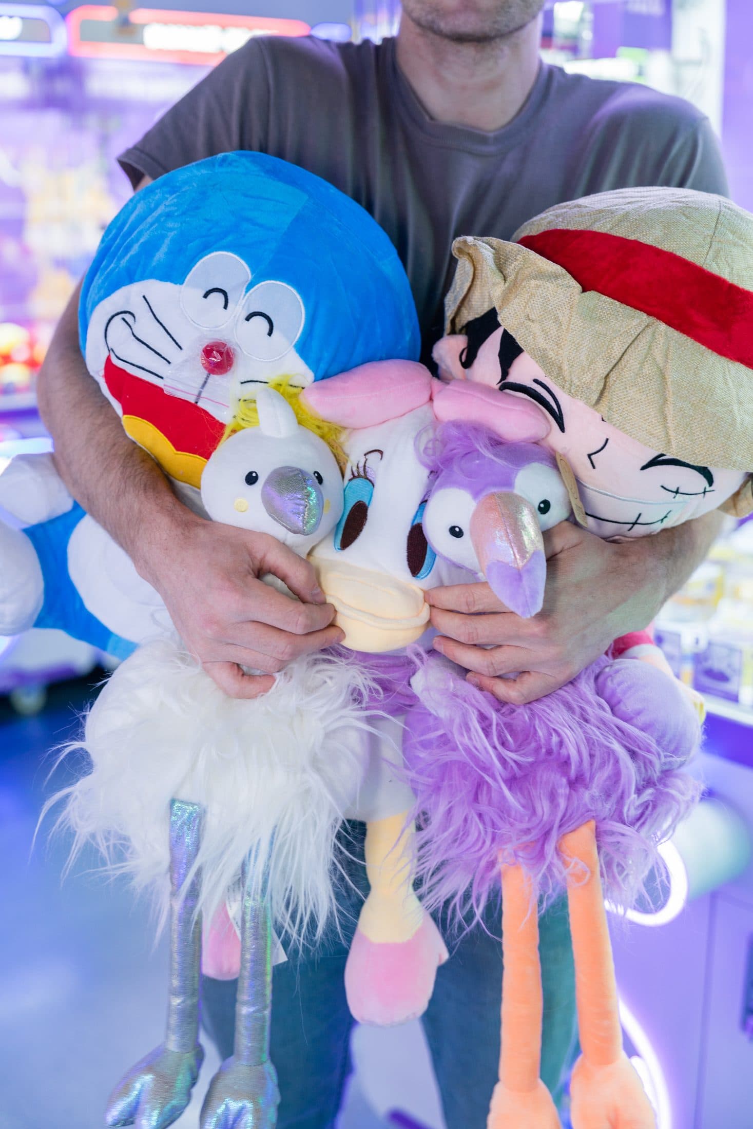 A guest carrying a tall stack of plush toys won from the claw machines.